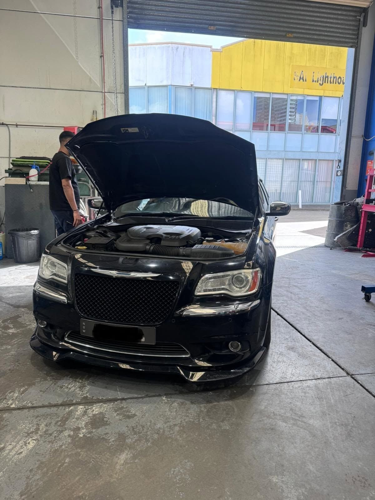 Mechanic working under the bonnet of a black Chrysler 300