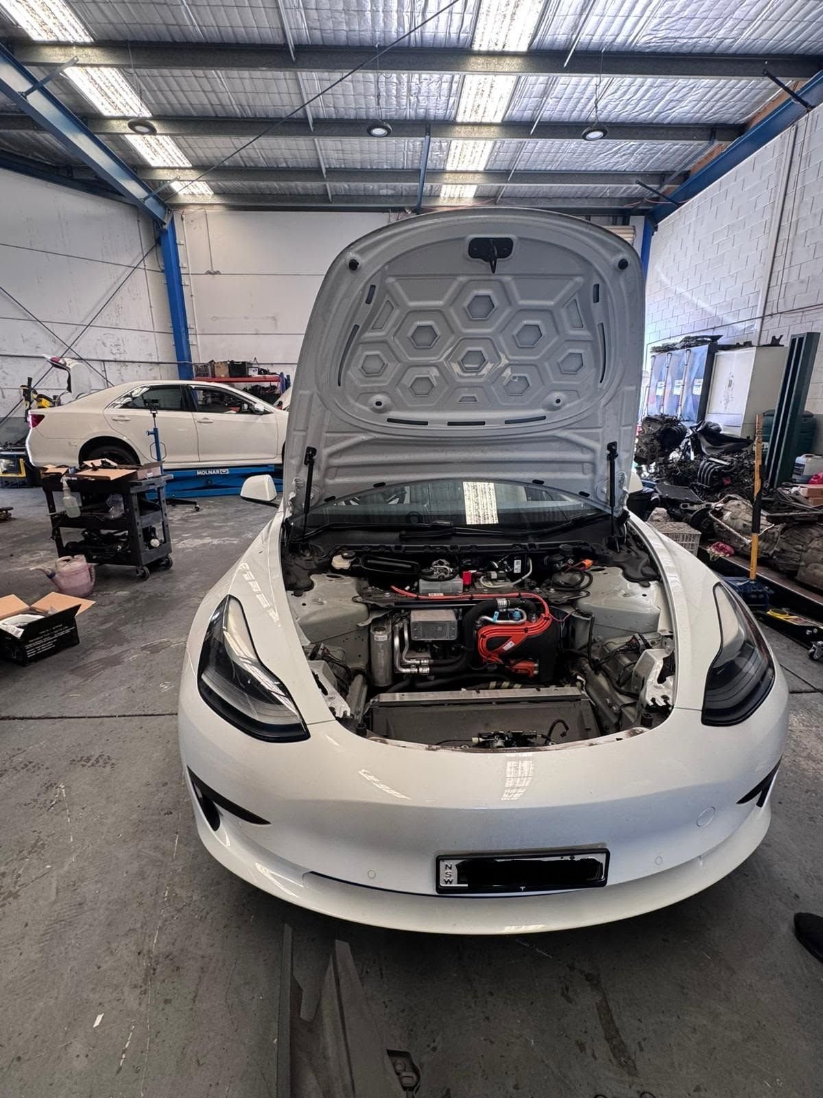 White Tesla Model 3 with the front boot open for service